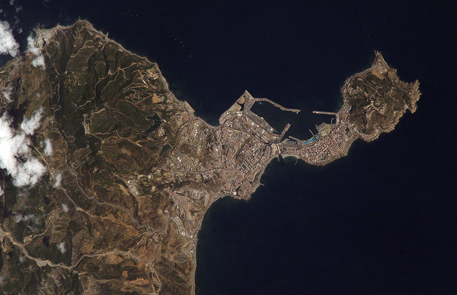 Ceuta on the northern African coastline is featured in this image photographed by an Expedition 15 crewmember on the International Space Station. The small Spanish enclave of Ceuta occupies a narrow isthmus of land on the African side of the Strait of Gibraltar. This view illustrates the sharp contrast in land cover between urban Ceuta (pink to white residential and industrial rooftops at center), the bay formed by seawalls to the north of the city, and the higher elevations of Monte Hacho forming the end of the isthmus. Green, vegetated slopes surround the Spanish fort atop the mountain, which commands a clear view of the Strait of Gibraltar to the northwest (not shown). Several small dots are visible near the coastline to the northwest and south of Ceuta -- these are small pleasure or fishing boats.
