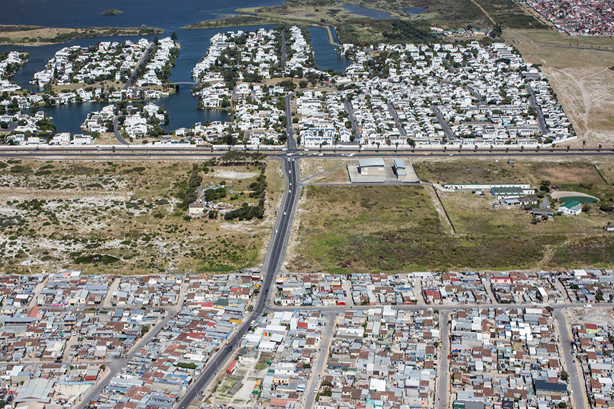 <em>An area of Muizenberg, Cape Town. In the foreground, the shacks and low-cost houses of Vrygrond township. In the background, the luxury homes of the Marina da Gama secure housing complex. South Africa has one of the highest levels of inequality in the world. (Mikael Colville-Andersen, CC BY 2.0)