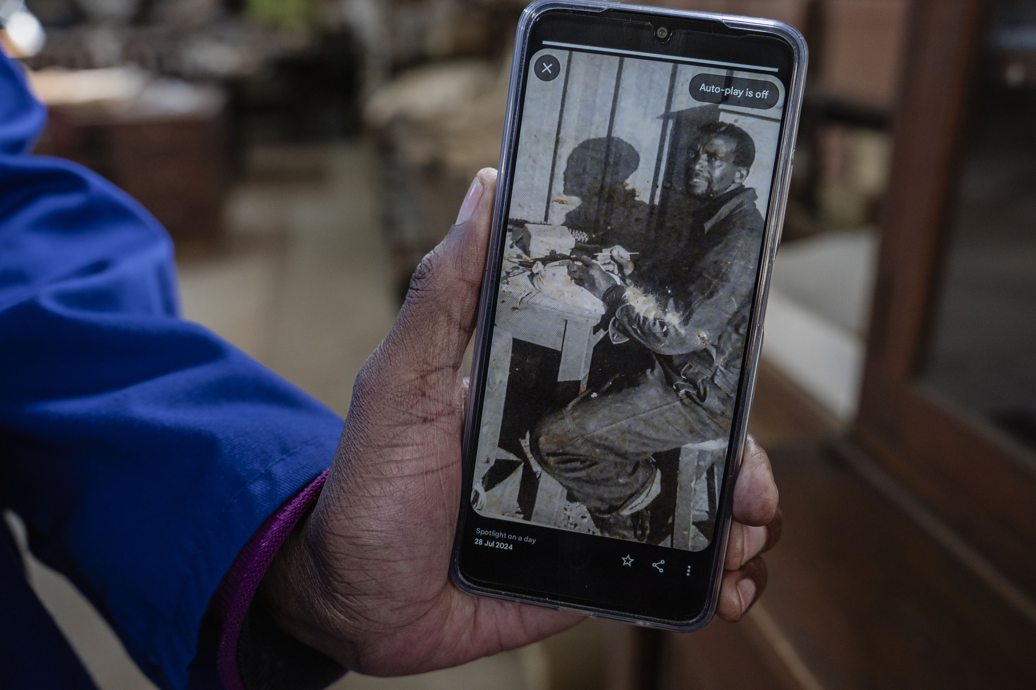 Fossil technician Abel Molepolle with an undated photo of his father David Molepolle, who joined the Sterkfontein Caves team in 1967. (Photo: Ihsaan Haffejee)